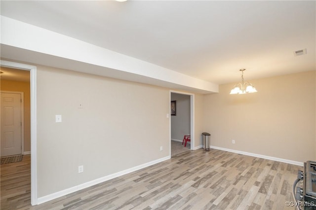 basement featuring light hardwood / wood-style flooring and a notable chandelier