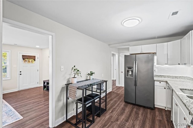 kitchen with light stone countertops, white cabinetry, appliances with stainless steel finishes, and dark hardwood / wood-style flooring