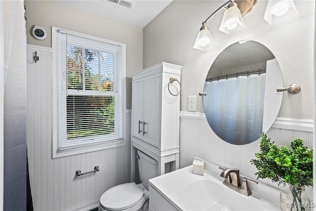 bathroom featuring toilet, vanity, and wooden walls