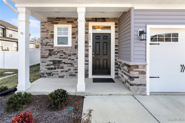 view of exterior entry featuring a porch and a garage