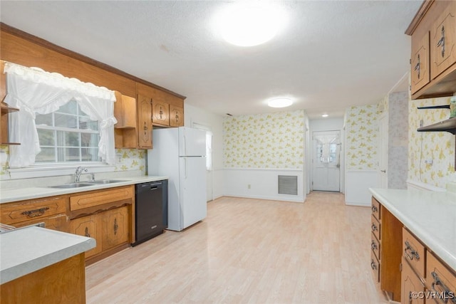 kitchen featuring sink, light hardwood / wood-style floors, black dishwasher, and white refrigerator