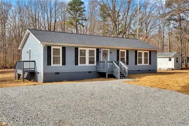 view of front of house with a storage shed, roof with shingles, crawl space, and an outdoor structure