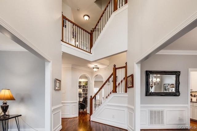 foyer entrance featuring a towering ceiling, ornamental molding, and dark hardwood / wood-style floors