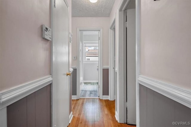 hallway featuring a textured ceiling and light hardwood / wood-style flooring