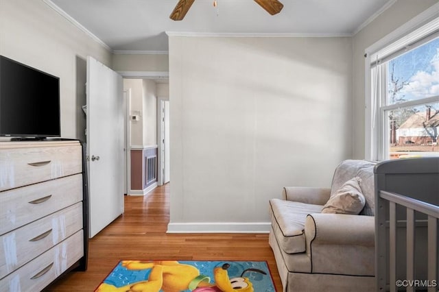 bedroom with ceiling fan, ornamental molding, hardwood / wood-style floors, and a crib