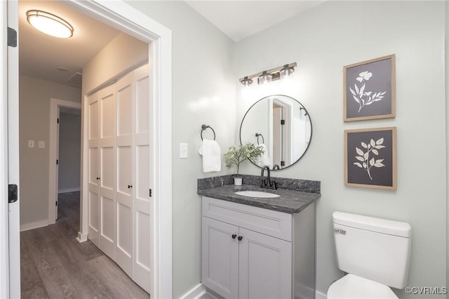 bathroom featuring toilet, vanity, and hardwood / wood-style flooring