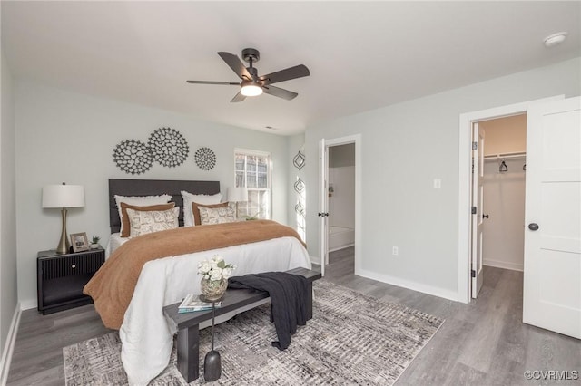 bedroom featuring a spacious closet, a closet, hardwood / wood-style floors, and ceiling fan