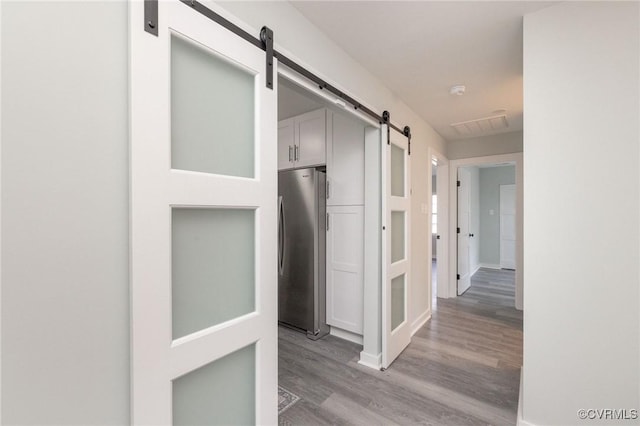 corridor with a barn door and light hardwood / wood-style flooring