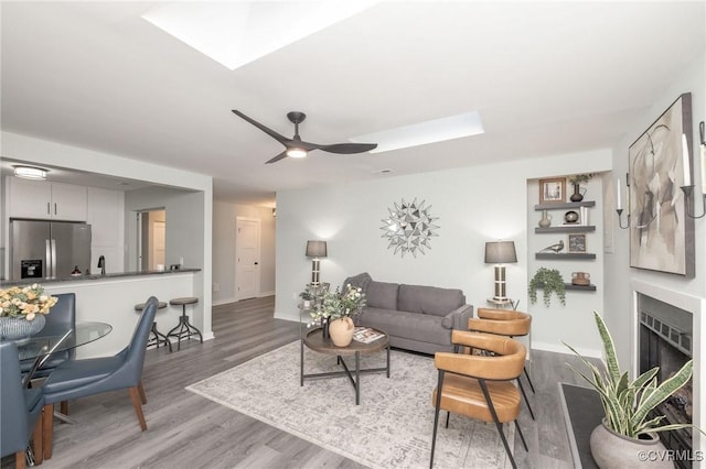 living room with hardwood / wood-style flooring, a skylight, and ceiling fan