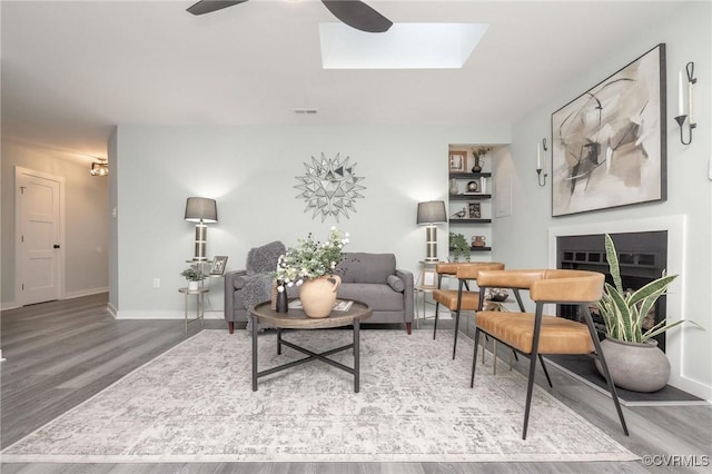 living room with ceiling fan, a skylight, and hardwood / wood-style floors