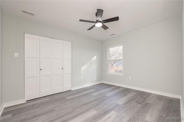 unfurnished bedroom with ceiling fan, a closet, and light wood-type flooring