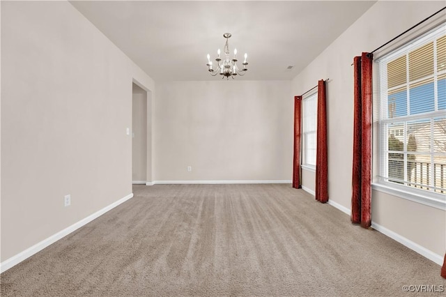 spare room with light carpet and a chandelier