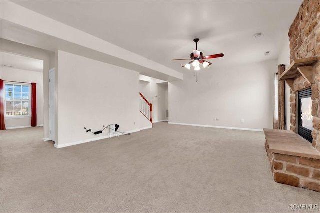 unfurnished living room with ceiling fan, carpet, and a stone fireplace