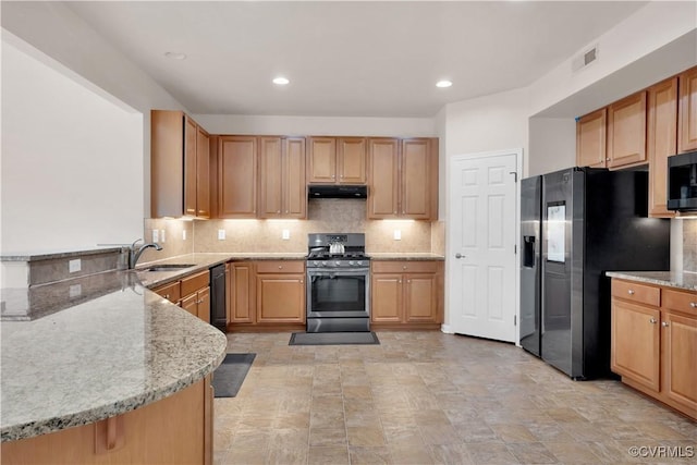 kitchen featuring light stone countertops, stainless steel appliances, kitchen peninsula, and sink