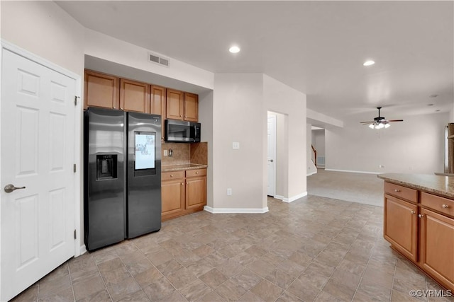 kitchen featuring ceiling fan, light stone counters, stainless steel fridge, and tasteful backsplash