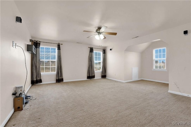 spare room featuring ceiling fan, light colored carpet, vaulted ceiling, and plenty of natural light