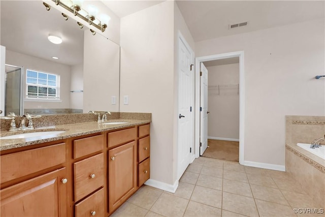 bathroom featuring plus walk in shower, vanity, and tile patterned flooring