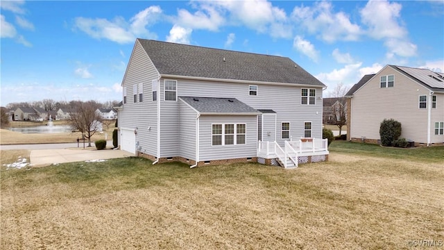 rear view of property featuring a garage, a wooden deck, and a lawn