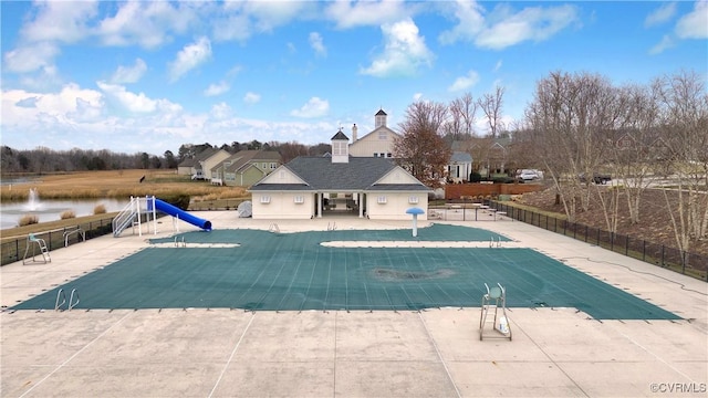 view of pool with a water view, a patio area, and a water slide