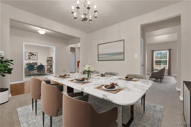 dining room featuring light carpet and a chandelier