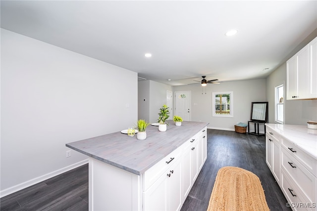 kitchen with dark wood-type flooring, white cabinetry, ceiling fan, and a center island