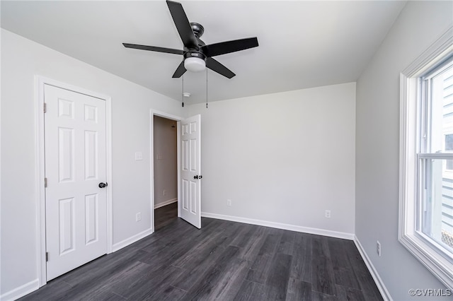 unfurnished bedroom featuring ceiling fan, dark hardwood / wood-style floors, and multiple windows