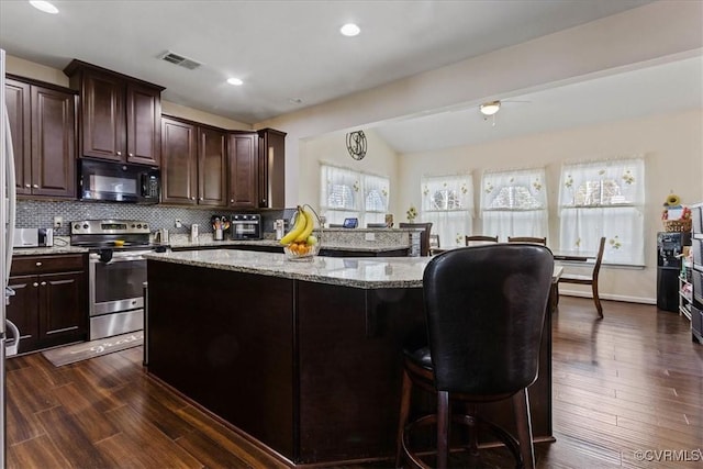 kitchen with dark hardwood / wood-style flooring, lofted ceiling, light stone counters, and stainless steel electric range