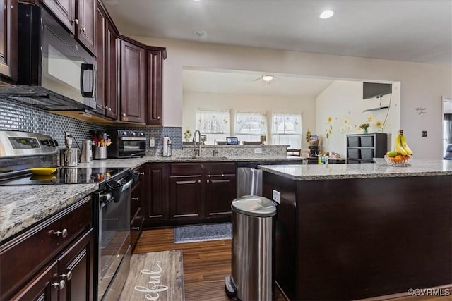 kitchen with appliances with stainless steel finishes, sink, backsplash, dark hardwood / wood-style flooring, and light stone countertops