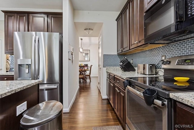 kitchen with appliances with stainless steel finishes, dark brown cabinets, light stone counters, and decorative backsplash