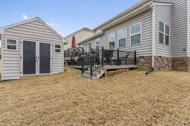 rear view of property with a shed, a lawn, and a deck