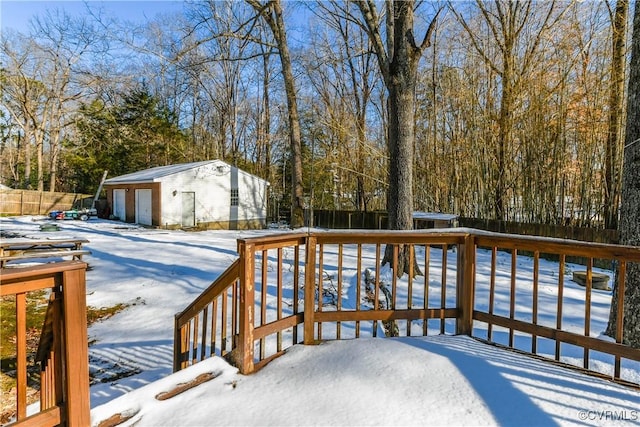 snow covered deck featuring a garage and an outbuilding