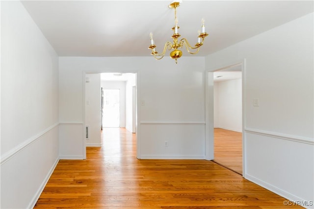 unfurnished room featuring an inviting chandelier and hardwood / wood-style floors