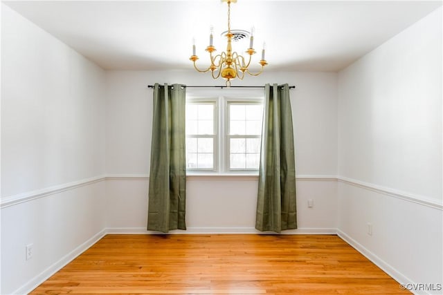 unfurnished room with light wood-type flooring and a chandelier