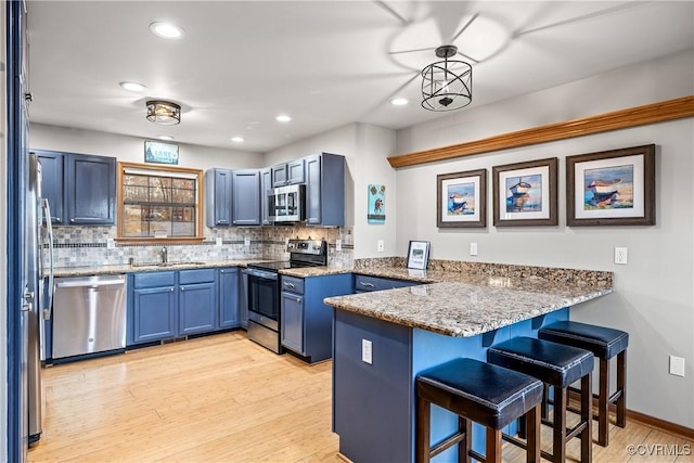 kitchen with pendant lighting, tasteful backsplash, blue cabinets, kitchen peninsula, and stainless steel appliances