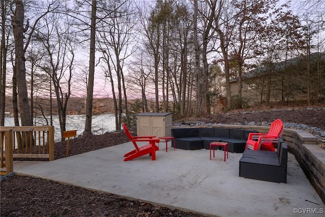 patio terrace at dusk featuring a water view and outdoor lounge area