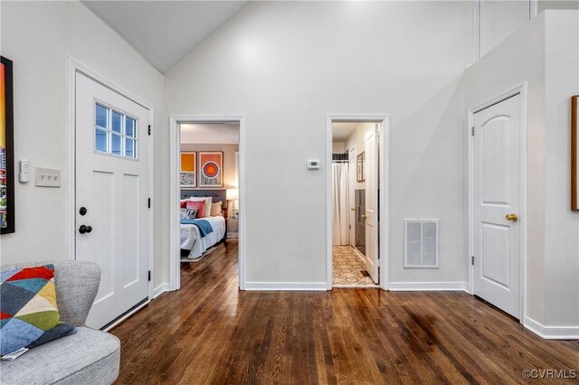 entryway featuring high vaulted ceiling and dark wood-type flooring