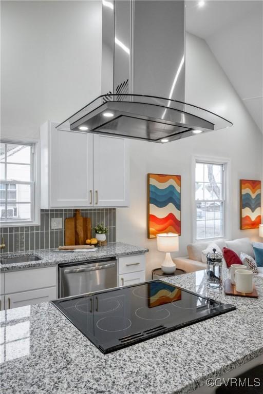 kitchen with island exhaust hood, black electric cooktop, vaulted ceiling, stainless steel dishwasher, and white cabinets