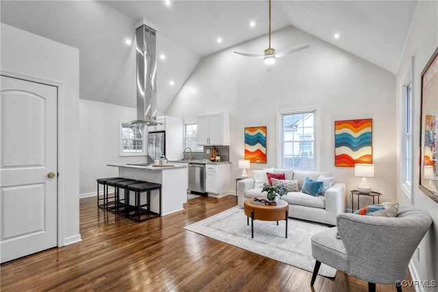 living room featuring high vaulted ceiling, ceiling fan, dark wood-type flooring, and sink