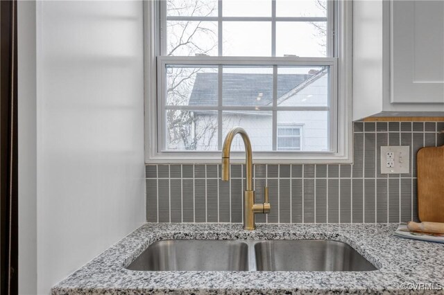 details featuring light stone countertops, sink, backsplash, and white cabinets