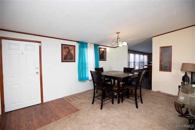 dining room with an inviting chandelier, crown molding, and carpet floors