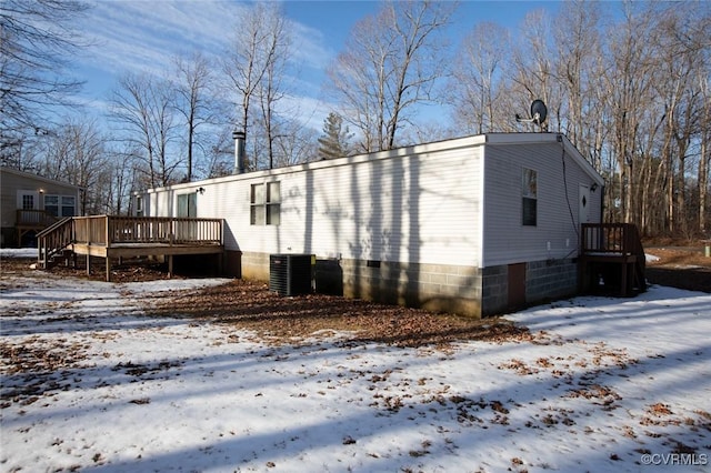 view of snowy exterior featuring central AC unit and a wooden deck