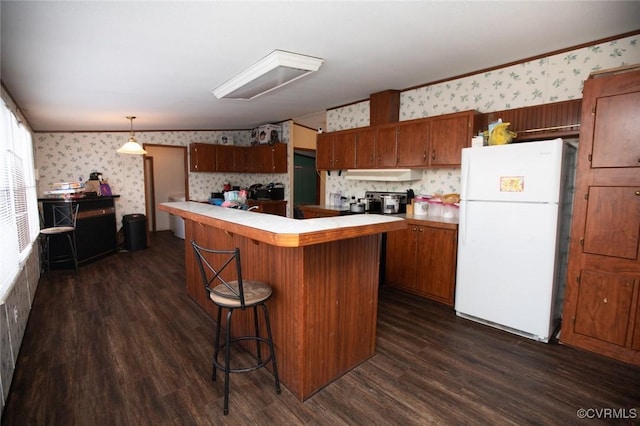 kitchen with a center island, hanging light fixtures, white refrigerator, and dark hardwood / wood-style flooring