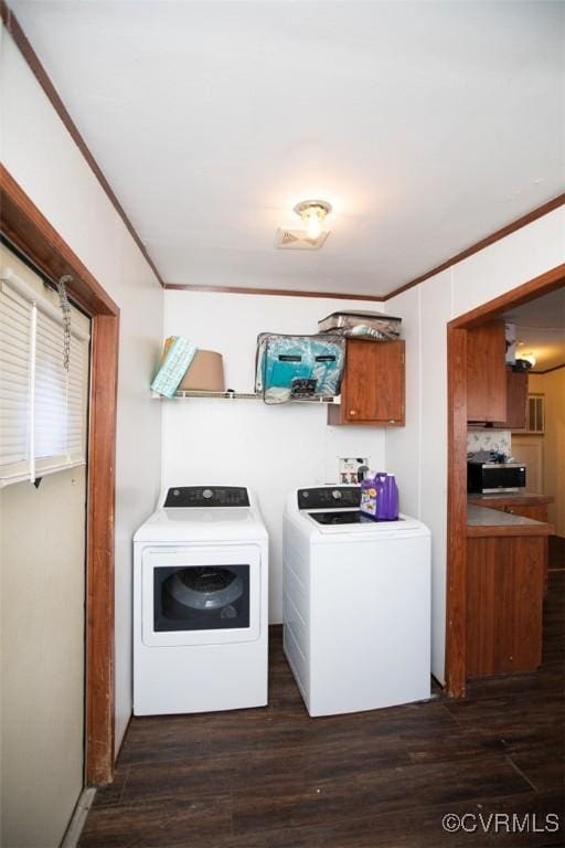 laundry area featuring cabinets, dark wood-type flooring, crown molding, and washing machine and clothes dryer