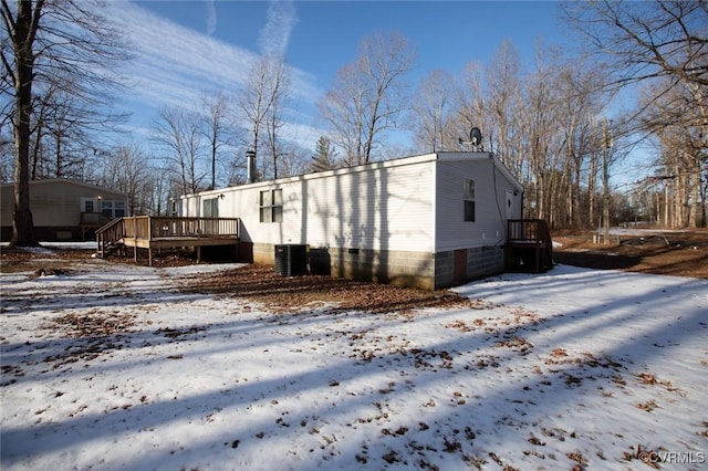 view of snow covered exterior with a wooden deck and central air condition unit