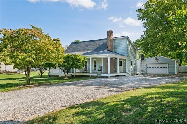 view of front of home featuring covered porch, a front yard, a garage, and an outdoor structure