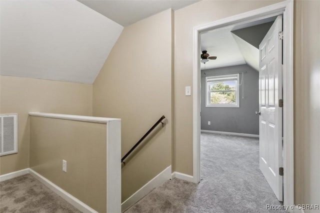 staircase featuring ceiling fan, vaulted ceiling, and carpet flooring