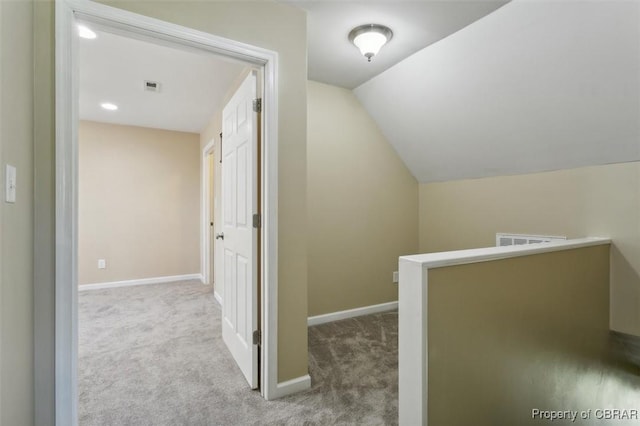 hallway with vaulted ceiling and light carpet