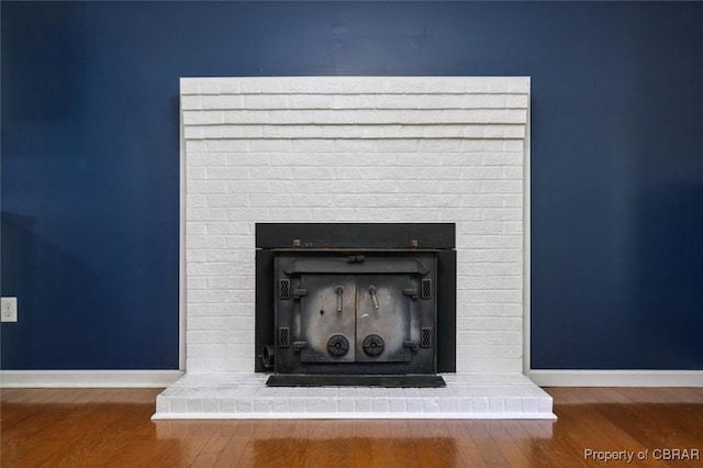 interior details with wood-type flooring and a brick fireplace