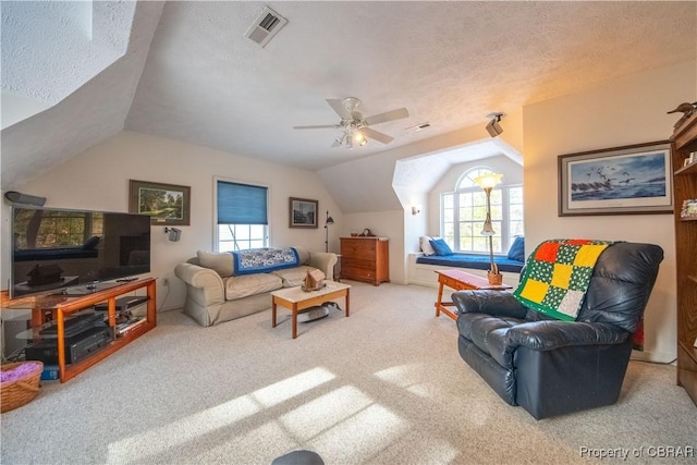 living room with ceiling fan, vaulted ceiling, a textured ceiling, and carpet flooring