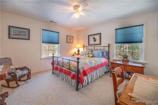 carpeted bedroom with ceiling fan and a textured ceiling